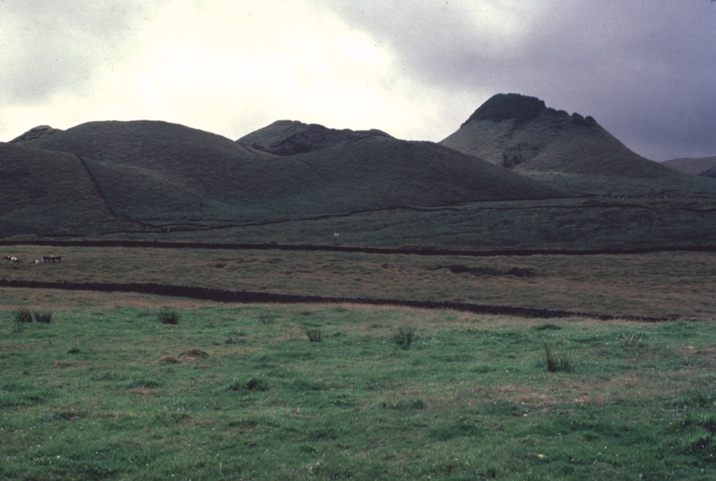 Terceira Island contains four stratovolcanoes constructed along a prominent ESE-WNW-trending fissure zone that cuts across the island.  Historically active Santa Barbara volcano at the western end of the island is truncated by two Pleistocene calderas.  The caldera is filled and surrounded by comenditic lava domes, such as the one at the right, which is located east of the caldera.  Historical eruptions have occurred from Pico Alto stratovolcano, the fissure zone between it and Santa Barbara, and from submarine vents west of Santa Barbara.   Copyrighted photo by Katia and Maurice Krafft, 1980.