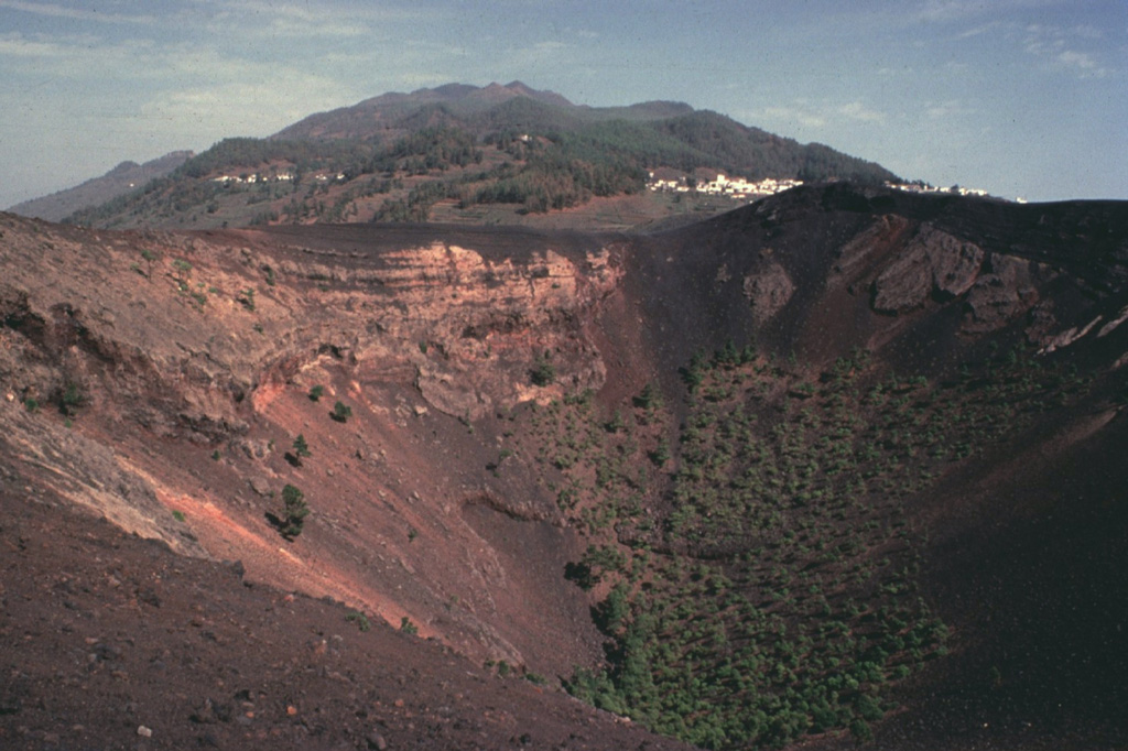 Cumbre Vieja, the southernmost of two large volcanoes forming the wedge-shaped island of La Palma, is one of the most active in the Canaries.  The elongated volcano is oriented N-S and has been the site of numerous historical eruptions, many of which produced lava flows that descended steeply to the sea.  Abundant cinder cones and craters line the crest of the volcano and dots its flanks.  Historical eruptions, recorded since the 15th century, have produced mild explosive activity and lava flows that damaged populated areas.  Copyrighted photo by Katia and Maurice Krafft, 1977.