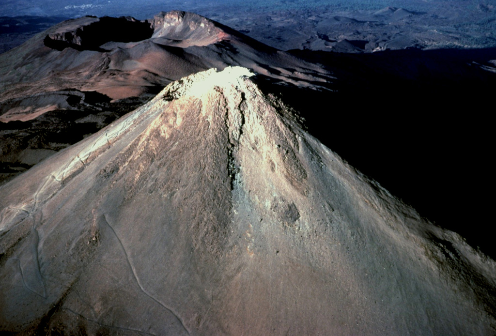 Pico de Teide, the highest peak in the Atlantic Ocean, towers 1700 m above the floor of Las Cañadas caldera.  The small nearly circular, 70-m-wide Caldereta crater truncates the summit of Pico de Teide.  The prominent 750-m-wide summit crater of Pico Viejo, another post-caldera stratovolcano, appears to the WSW beyond the summit of Pico de Teide. Copyrighted photo by Katia and Maurice Krafft, 1977.