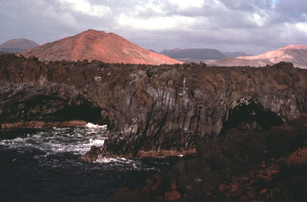 The 60-km-long island of Lanzarote at the NE end of the Canary Islands contains the largest concentration of youthful volcanism in the Canaries.  Cinder cones and lava flows erupted along NE-SW-trending fissures in the Pleistocene and Holocene are found throughout the low-altitude arid island.  The largest historical eruption of the Canary Islands took place during 1730-36, when long-term fissure-fed eruptions formed the Montañas del Fuego group of cinder cones and produced voluminous lava flows that covered about 200 km2.   Copyrighted photo by Katia and Maurice Krafft, 1977.