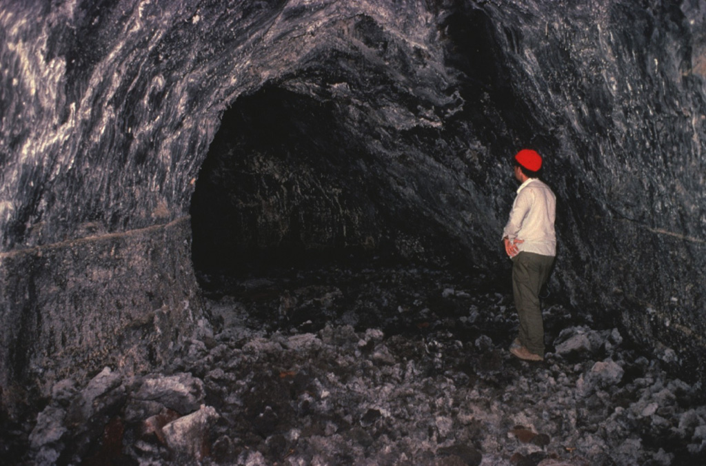 Volcanologist Maurice Krafft observes a lava tube on Lanzarote Island.  Lava tubes provide an efficient means of transporting molten lava through subsurface channels that are thermally insulated from the surface.  Many spectacular examples of lava tubes are found on Lanzarote, including the Ceuva de los Verdes lava-tube system, which extends more than 5 km from Volcán la Corona cinder cone to the Atlantic coast. Copyrighted photo by Katia and Maurice Krafft, 1977.