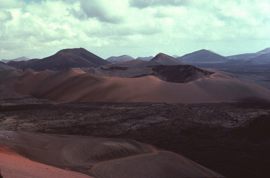 Caldera del Corazoncillo (center), also known as Caldera de Fuencaliente, was active during a two-week period in September 1730, which initiated the 1730-36 Montañas del Fuego eruption on Lanzarote.  The NE-SW-trending eruptive fissures were located slightly west of the low crest of the island, and most of the extensive lava flows reached the coast along a broad 20-km-wide front on the western side of the island.  Only one lava flow reached the eastern coast.  Copyrighted photo by Katia and Maurice Krafft, 1977.