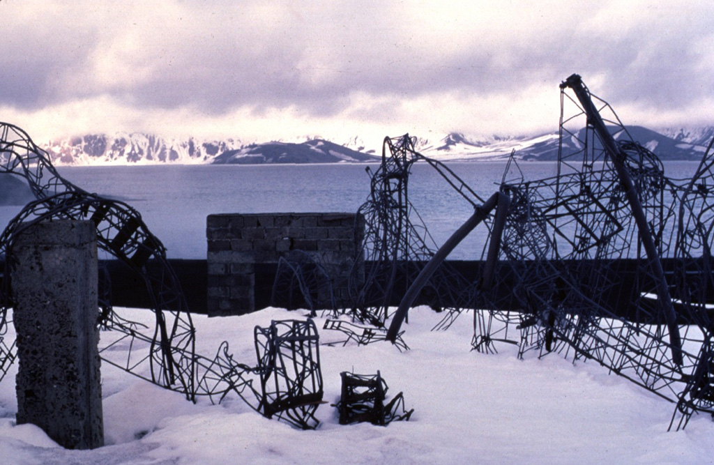 These twisted girders are remnants of the Chilean Antarctic reseach station on the NE side of Deception Island.  The 1969 eruption from vents along the east side of the caldera bay damaged or destroyed the Chilean and British scientific bases, as well as the island's whaling station.  The 1969 eruption took place from a roughly N-S-trending line of vents that cut a glacier west of Mount Pond. Copyrighted photo by Katia and Maurice Krafft, 1984.