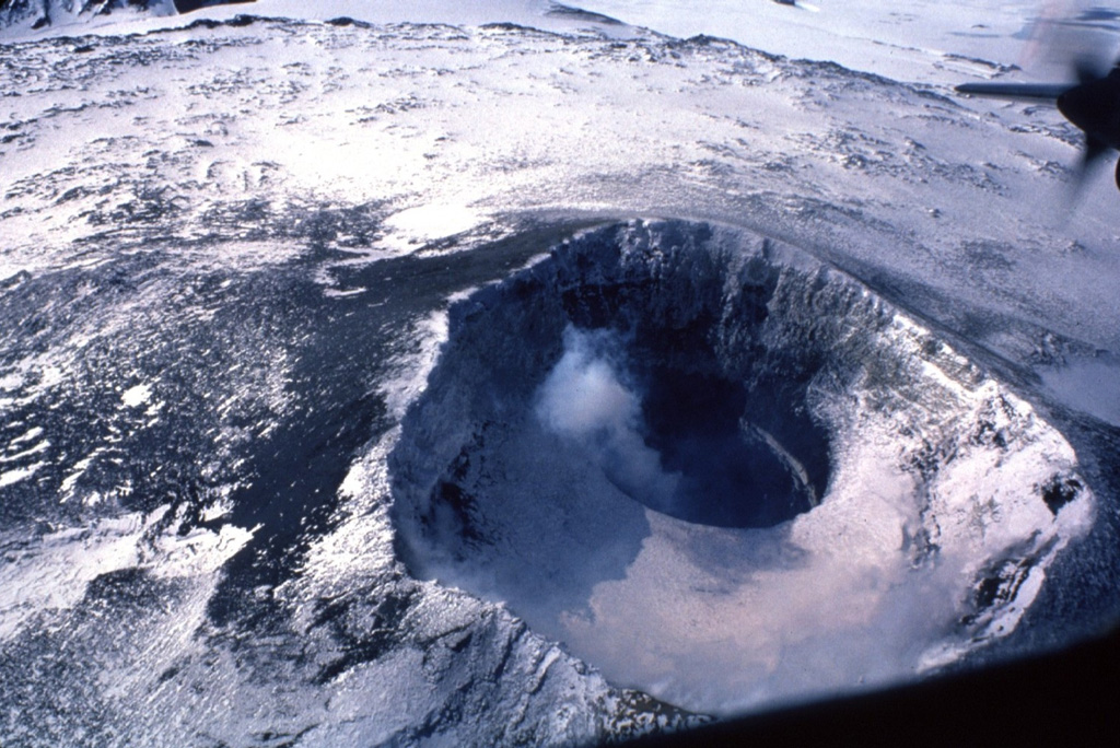 The summit of Antarctica's Mount Erebus is the world's southernmost active volcano. It contains an elliptical 500 x 600 m wide crater whose NE side contains a 250-m-wide, 100-m-deep inner crater. The flat, snow-covered floor of the Main Crater is about 100 m below its rim. A plume rises from the inner crater that has contained an active lava lake since 1972. Photo by Bill Rose, 1983 (Michigan Technological University).