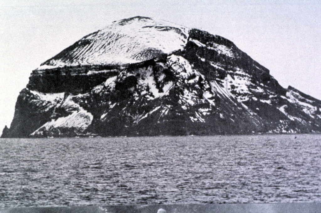 The steep Bridgeman Island, seen here from the SE, is a 600 x 900 m remnant of a much larger volcanic edifice that is mostly submerged. The base displays bedded pyroclastic rocks, and an erosional surface cut into these rocks is filled by horizontal lava flows (left center). The extensively eroded island does not display youthful volcanic features. Photo by Oscar González-Ferrán (University of Chile).