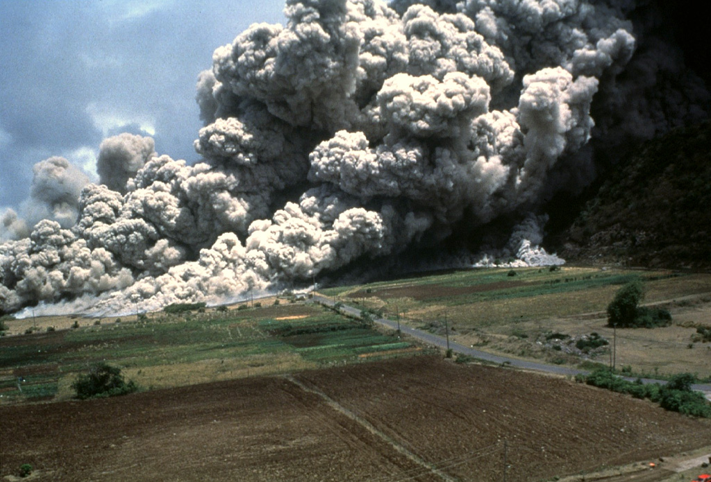 A devastating pyroclastic flow on 25 June 1997 sweeps across the lower NE flank of Soufrière Hills volcano on Montserrat. More than two dozen people within the officially evacuated zone were killed. This eruption sent an ash plume to ~10 km altitude and produced pyroclastic flows and surges that overran both vacated and partly inhabited NE-flank settlements, destroying 100-150 houses in eight villages within the restricted zone. The pyroclastic flow traveled 4.5 km and almost reached the sea. Photo by Paul Cole, 1997 (Montserrat Volcano Observatory).