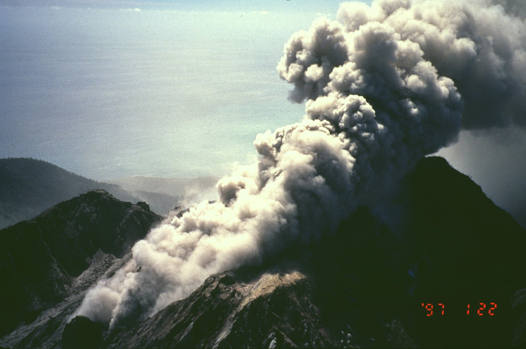 An ash column rises above Soufrière Hills volcano in January 1997.  Intermittent phreatic eruptions began at Soufriere Hills on July 18, 1995.  A new lava dome started growing in English Crater in September 1995 and eventually filled much of the crater.  Pyroclastic flows accompanying dome growth initially were restricted to the eastern flanks, but eventually traveled in all directions, making the entire southern half of the island uninhabitable.  In August 1997, pyroclastic flows destroyed much of Plymouth, the former capital of Montserrat. Photo by Mark Davies, 1997 (Montserrat Volcano Observatory).