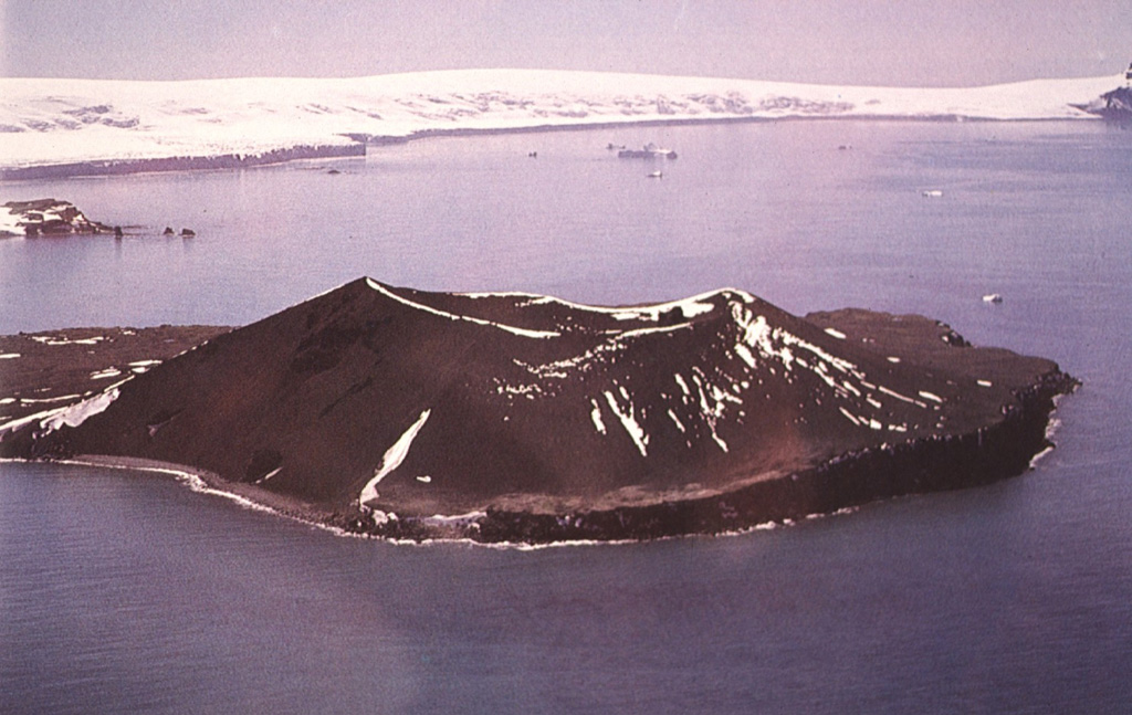 The small 1.4 x 1.7 km Penguin Island, seen here from the SW, is located off the SE coast of King George Island in the South Shetland Islands. The most prominent feature is Deacon Peak (center), a largely basaltic scoria cone with a 350-m-wide summit crater. Petrel Crater, a 300-m-wide maar, is located behind Deacon Peak, out of view in this photo. Both Deacon Peak and Petrel Crater were formed within the past few hundred years. Photo by Oscar González-Ferrán (University of Chile).