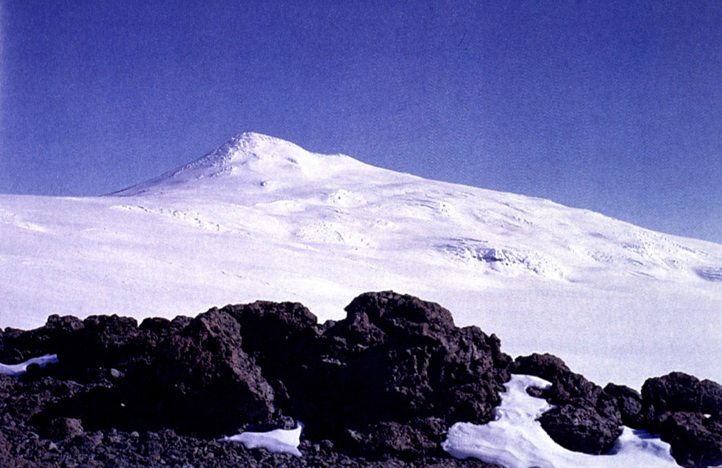 Mount Berlin is seen here from Mount Moulton to the east and is located in the Flood Range of Marie Byrd Land, near the eastern coast of the Ross Sea. Major features include Berlin Crater and Merrem Peak, with active fumaroles around the western and northern Berlin Crater rims. Photo by Oscar González-Ferrán (University of Chile).
