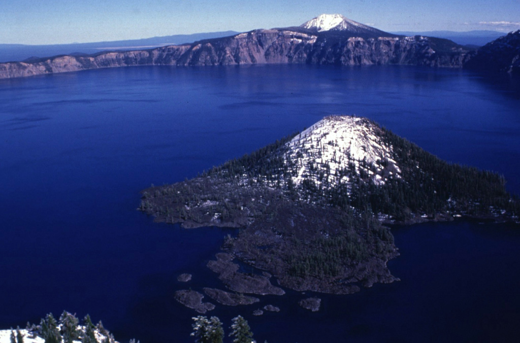The lake within Crater Lake is the deepest in the USA at nearly 600 m, within the caldera that formed during a major eruption of its predecessor Mount Mazama around 7,700 years ago. Snow mantles the summit of the Wizard Island cone in the foreground. Photo by Lee Siebert, 1997 (Smithsonian Institution).