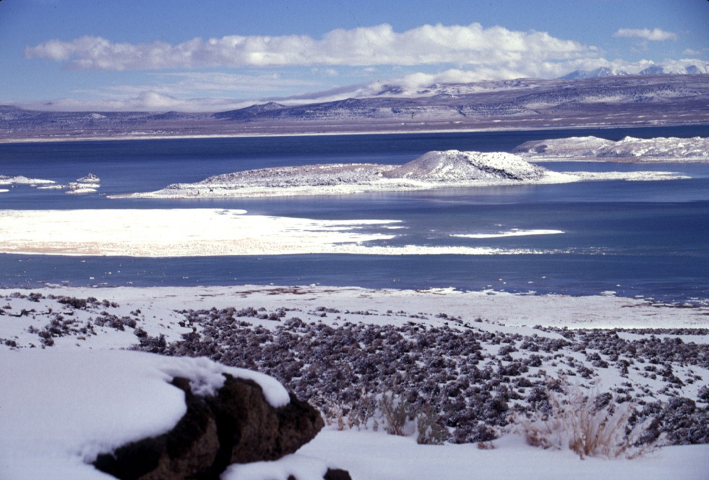 Negit (right-center) and Paoha (far right) islands in Mono Lake are seen from Black Point, a basaltic cone on the NW shore of the lake.  The most recent eruptive activity from the Mono Lakes volcanic field took place 100-230 years ago, when lake-bottom sediments forming much of Paoha Island were uplifted by intrusion of a rhyolitic cryptodome.  Black Point is an initially sublacustral cone that formed about 13,300 years ago when the lake was higher.  The White Mountains form the far right horizon. Photo by Lee Siebert, 1997 (Smithsonian Institution).
