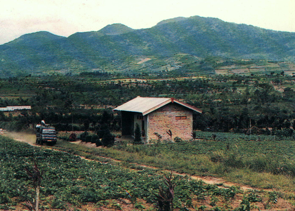 Gunung Kaba, rising above farmlands at Pematang Danau, has three large historically active craters trending ENE from the summit to the upper NE flank. The SW-most crater is the largest. Most historical activity has consisted of explosive eruptions that affected only the summit region of the volcano. They originated from the central summit craters, although the upper-NE flank crater Kawah Vogelsang also produced explosions during the 19th and 20th centuries. Photo by Setiadarma, 1989 (Volcanological Survey of Indonesia).