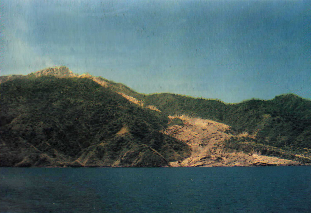 Paluweh volcano is seen here in April 1985, shortly after a brief explosive eruption from a vent near the 1981 lava dome. It forms an 8-km-wide island located N of the volcanic arc of Flores Island. The summit region contains overlapping craters and lava domes, and several flank vents occur along a NW-trending fissure.  Photo by Sumailani, 1985 (Volcanological Survey of Indonesia).