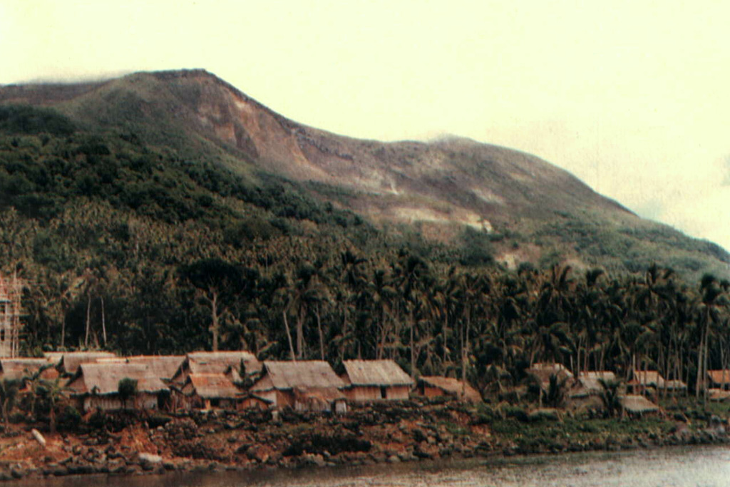 Gunung Wurlali volcano rises above Teluk Kuluwati village on its southern flank.  The 868-m-high stratovolcano (also known as Damar) rises 3800 m above the Banda Sea floor. Photo by S. Siswowidjojo, 1978 (Volcanological Survey of Indonesia).