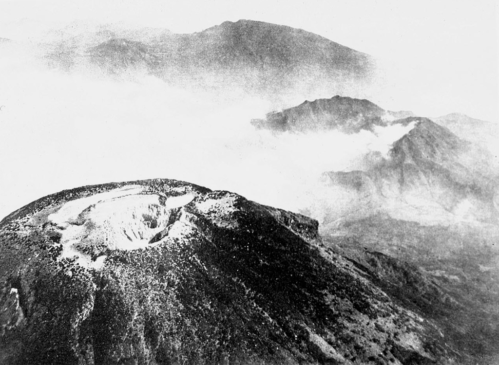 An aerial view looking towards the NW across the summit crater complex of Sundoro volcano. The forested peak at the top center is Gunung Prahu, the largest cone of the Dieng volcanic complex. Photo published in Taverne, 1926 