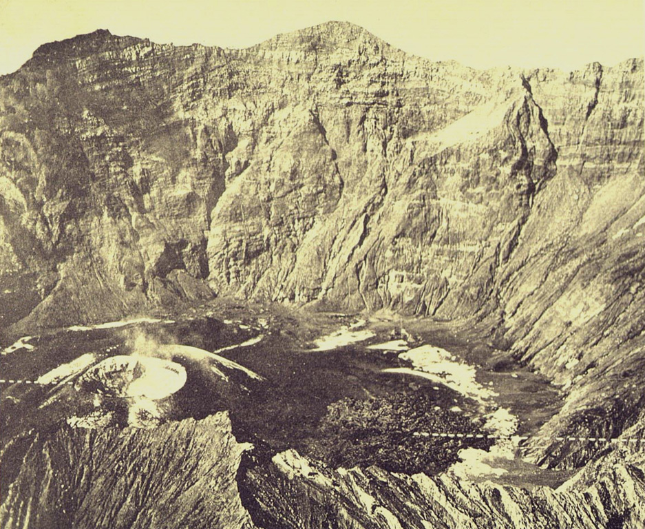The cone at the lower left on the floor of Raung's summit caldera formed during an eruption in 1913. A lava flow erupted from the cone, extending to the right across the caldera floor. This aerial photo, taken some time before 1926, shows the steep, roughly 500-m-high SW caldera wall in the background. Photo published in Taverne, 1926 