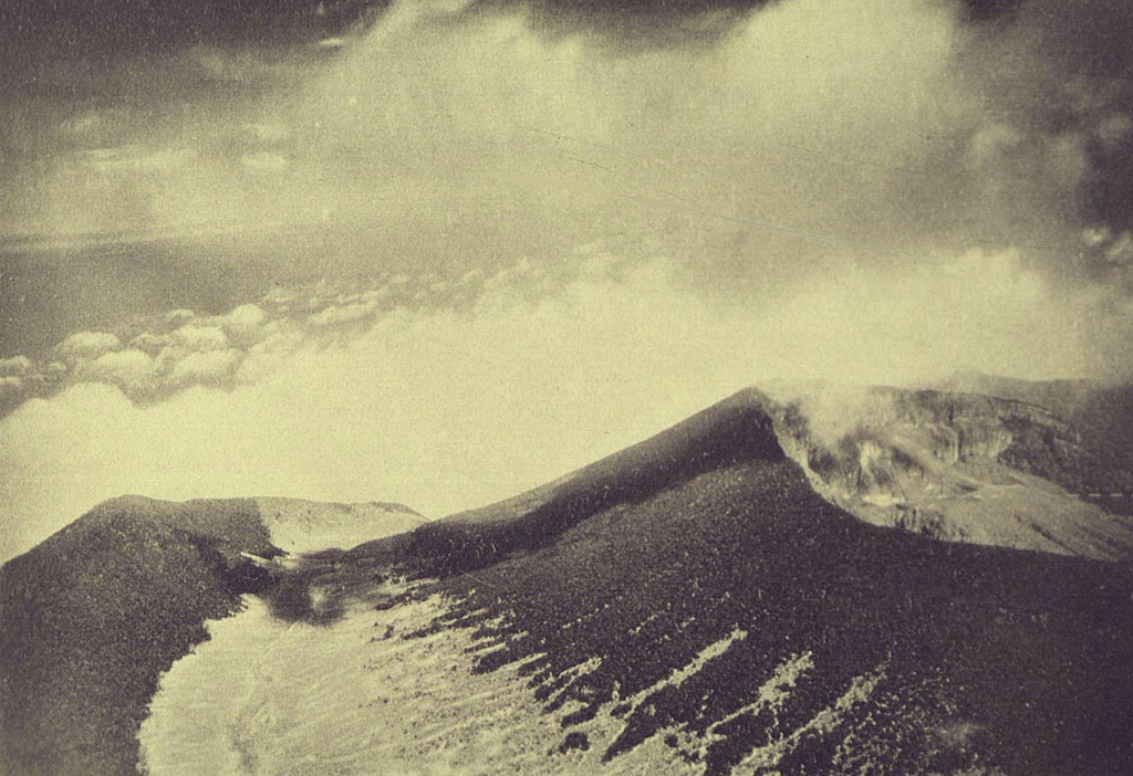 An aerial view from the NE shows the summit crater (right) of Gede volcano. The summit cone was constructed within an older crater, with the western rim forming the peak to the left. Photo from Taverne, 1926, 