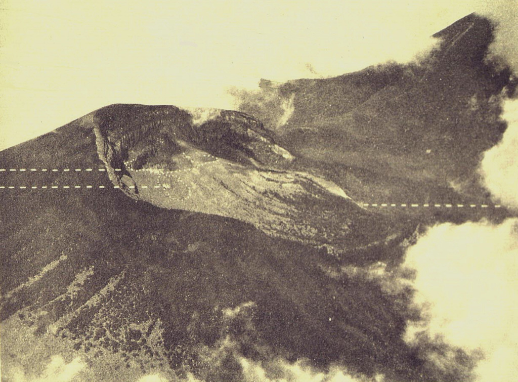 An aerial photo shows the partially forested summit of Gunung Gede volcano from the east. The two dashed lines to the left indicate the locations of Kawah Ratu (top) and Kawah Lanang craters (bottom), and the dashed line to the right indicates the site of Kawah Wadon crater. The flank of Gunung Pangrango, adjacent to Gede, is to the upper right. Photo published in Taverne, 1926 