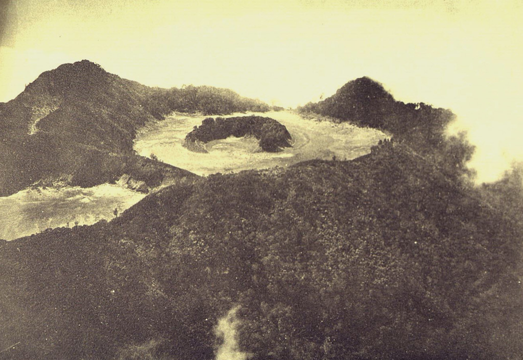 Gunung Merapi, constructed on the eastern rim of Ijen caldera, is the volcano's highest peak. The summit of Gunung Merapi, seen here in an aerial view from the NW, is truncated by a flat-floored crater that contains an arcuate forested rim of a cone.  Photo published in Taverne, 1926 