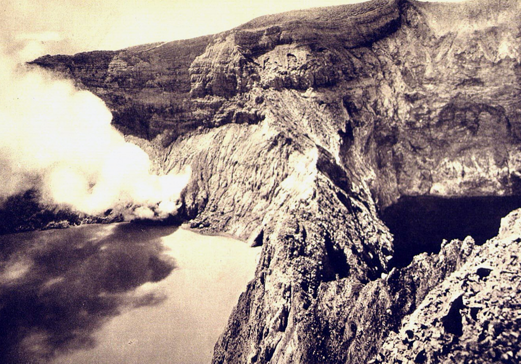 A plume rises from a fumarole on the crater wall of light-colored Tiwu Nua Muri Kooh Tai lake. A sharp ridge separates the crater lake from the dark-colored Tiwu Alta Polo lake (right), the easternmost of the two craters.  Photo by E. Weissenborn (published in Kemmerling 1929, 