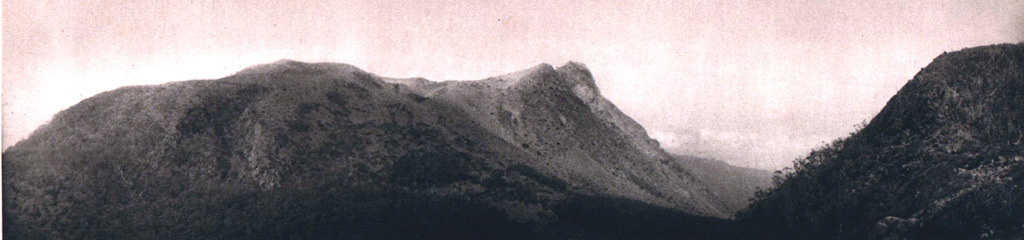 The high point on the rim of the active summit crater of Egon is visible at center, with an older crater rim and possible lava dome at left and in the foreground. The northern coast of Flores Island is visible in the gap, just left of another older ridge in the summit area at right. Photo published in Kemmerling 1929, 