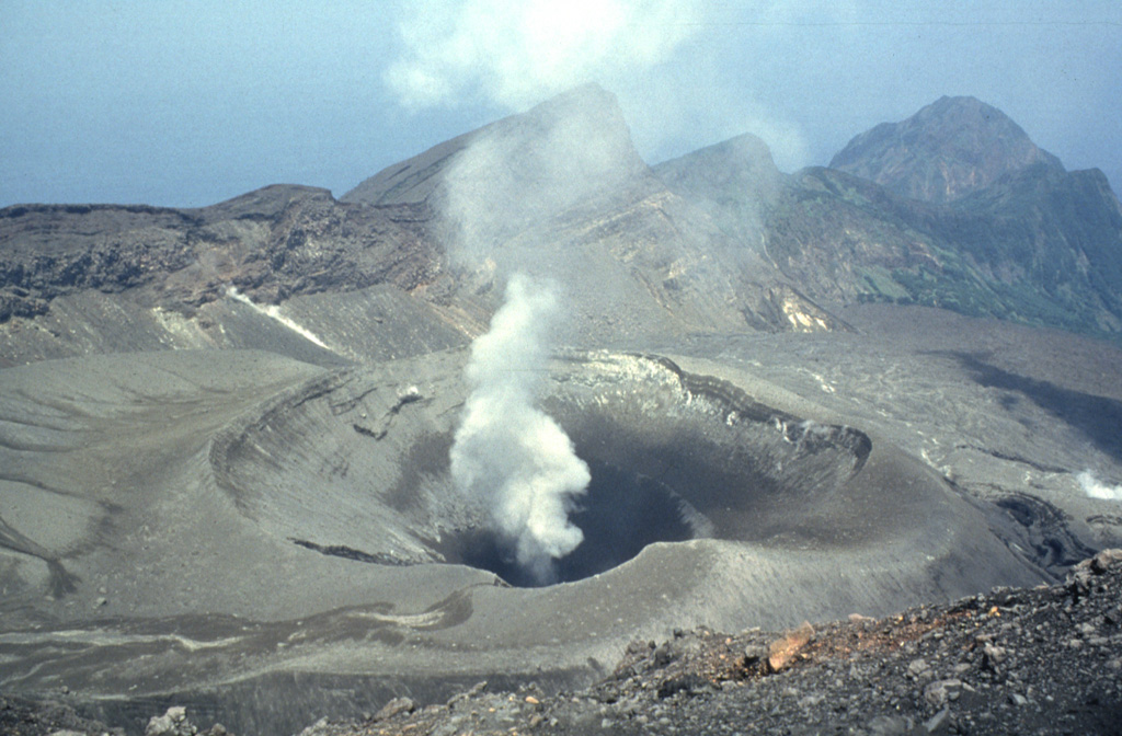 A plume rises above Ontake, the summit crater of Suwanosejima. The 8-km-long island consists of a stratovolcano with two historically active summit craters. The dipping scarp at the top of the image opens towards the sea on the E flank and formed by edifice collapse. This is one of Japan's most frequently active volcanoes and has been in a state of intermittent Strombolian activity since 1949. Photo by Yukio Hayakawa, 1998 (Gunma University).