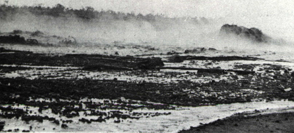 Steam rises from the surface of a hot secondary lahar in the Temas river on 19 May 1966, three weeks after a devastating eruption on 26-27 April. During the eruption lahars reached 31 km down the Temas river to the SW. The Temas river lahars were part of the main flow that originated in the Badak river channel below the southwestern low point of the crater rim. Primary lahars caused most of the more than 200 fatalities from the eruption, but three people were also killed by secondary lahars such as the one seen in this photo. Photo by I. Suryo, 1966 (Volcanological Survey of Indonesia).