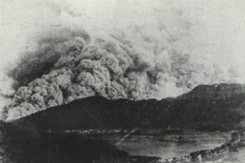 A pyroclastic flow in 1966 sweeps down the western flank of Awu volcano above the city and harbor of Tahuna.  A major explosive eruption on August 12 ejected the lava dome and crater lake.  Pyroclastic flows descended all sides of the volcano for an average distance of 5 km.  There were 39 fatalities, and 1000 people were injured.  Detonations were heard in the Philippine Strait.  Following the paroxysmal eruption on the 12th, diminished explosive activity continued.  The volcano was quiet in September, but three small eruptions occurred in October. Photo by J. Matahelumual, 1966 (Volcanological Survey of Indonesia).