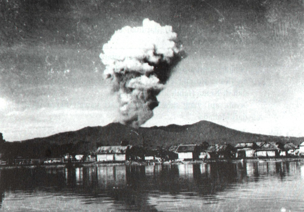 An eruption plume rises from Tompaluan crater above the coastal city of Manado on June 22, 1959.  This was part of intermittent eruptive activity from Lokon-Empung volcano that began on February 17, 1958 and lasted until December 23, 1959.  Ash and incandescent material was frequently ejected, affecting nearby villages.  The peak at the right is Gunung Tatawiran, a volcanic cone immediately to the west of the historically active Lokon-Empung volcanic complex. Photo courtesy of Volcanological Survey of Indonesia, 1959.