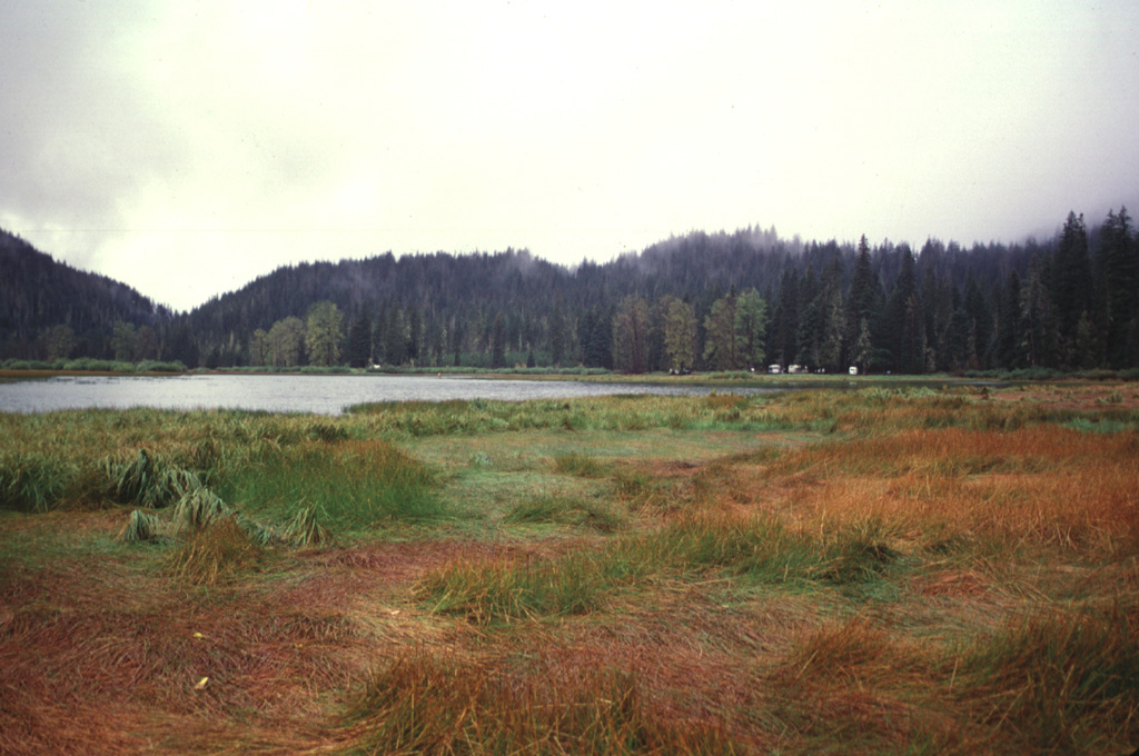 The Lost Lake scoria cones, seen here from the east across Lost Lake near Santiam Pass, are the youngest known volcanic products of the Sand Mountain volcanic field. The cones formed about 1,950 radiocarbon years ago during eruptions along a N-S-trending fissure at the northern end of the Sand Mountain group. Growth of the cones blocked Lost Creek, forming Lost Lake. Photo by Lee Siebert, 1997 (Smithsonian Institution).