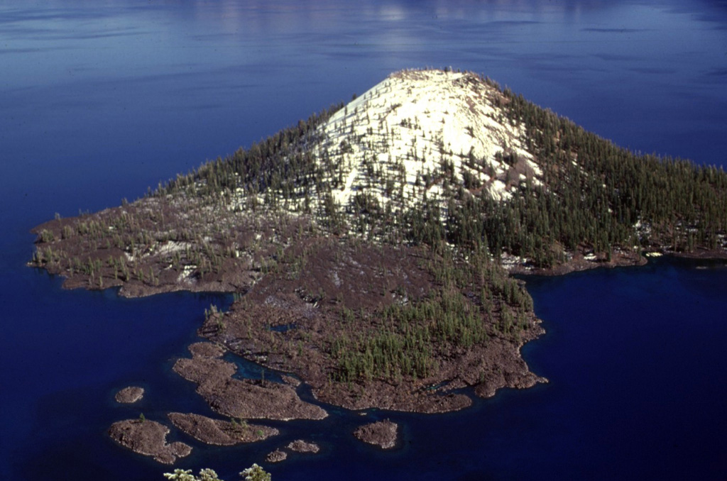 The Wizard Island cone formed while the lake was still filling the Crater Lake caldera. The cone grew near the western structural margin of the caldera on top of a broader central platform of lava flows, and the visible portion represents about 2% of post-caldera eruptive products, the rest of which are below the lake surface. Photo by Lee Siebert, 1997 (Smithsonian Institution).
