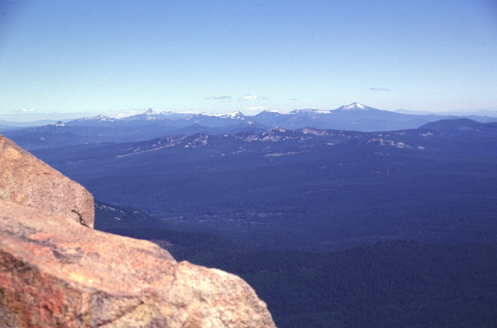 The snow-mantled peaks on the northern horizon are the remnants of Mount Mazama, seen here from the summit of Mt. McLoughlin. Mount Mazama was a complex of overlapping edifices that was once one of Oregon's largest volcanoes, until it collapsed about 7,700 years ago and formed the 8 x 10 km Crater Lake caldera. The highest peak to the right is Mount Scott, part of a pre-caldera edifice east of the caldera rim.  Photo by Lee Siebert, 1998 (Smithsonian Institution)