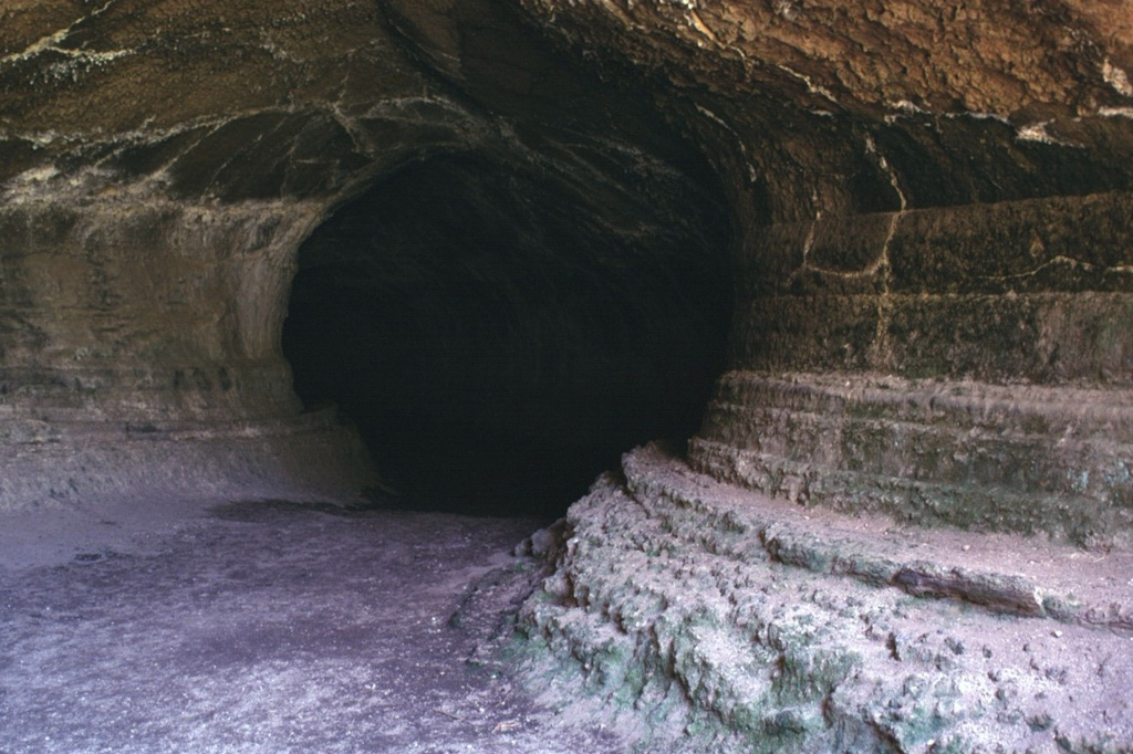 Lava Beds National Monument contains nearly 300 lava-tube caves associated with fluid basaltic lava flows on the flanks of Medicine Lake volcano in northern California.  The sides of this large lava tube, known as Valentine Cave, show the pronounced "bathtub rings" left by lava flowing through the tube.  Valentine Cave is an example of a lava tube from which lava almost completely drained.  The Valentine lava flow was erupted about 10,850 radiocarbon years ago, and is one of the largest flows on the northern flank of Medicine Lake caldera. Photo by Lee Siebert, 1998 (Smithsonian Institution).