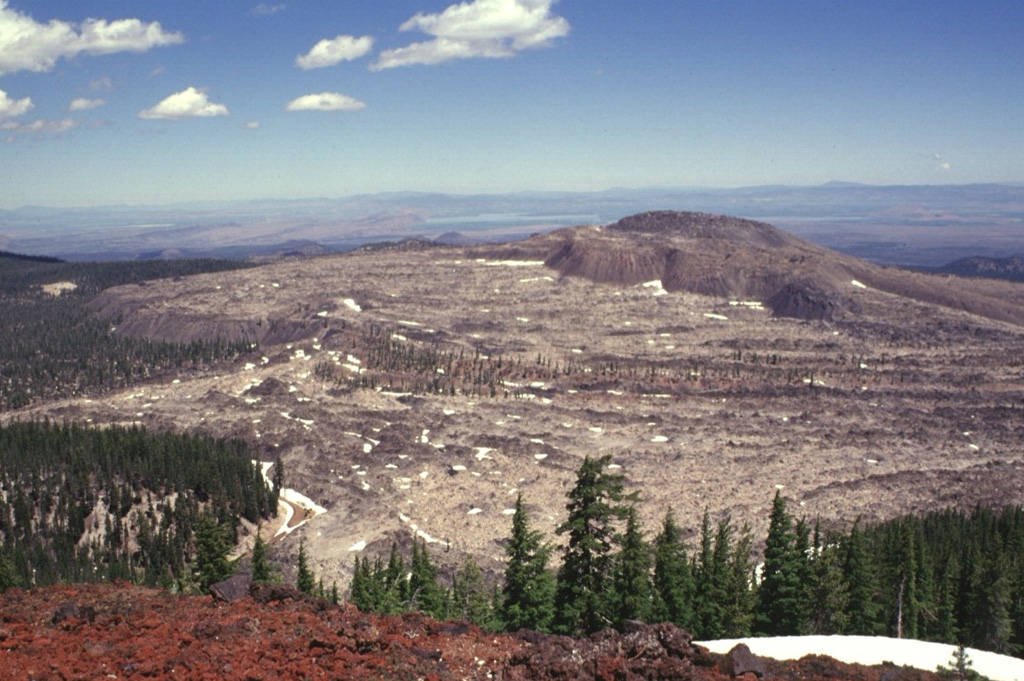 The Glass Mountain obsidian flow, seen here from Lyons Peak on the east rim of Medicine Lake caldera, was erupted from a series of vents just outside the buried inferred eastern rim of the caldera.  The youthful, steep-sided rhyolitic and dacitic flow is both the largest and youngest of a series of Holocene rhyolitic and dacitic flows at Medicine Lake.  The 1 cu km flow was erupted about 900 years ago.  The flow traveled a short distance west (left) into the caldera, but mostly flowed down the eastern flank, reaching a point about 6 km from its source. Photo by Lee Siebert, 1998 (Smithsonian Institution).