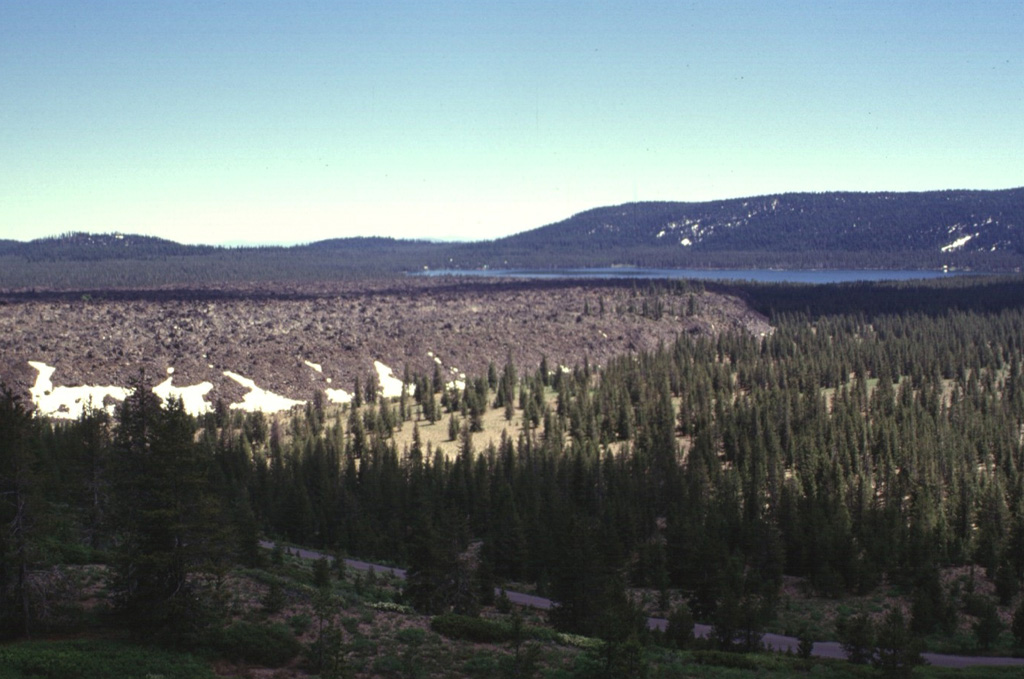 The Medicine Lake lava flow, seen here from the NW with Medicine Lake in the background, was erupted onto the caldera floor from a vent near the northern caldera rim. The flat-lying, viscous 0.08 km3 lava flow is not precisely dated, but is known from stratigraphic evidence to have been emplaced sometime between the roughly 780 BCE Burnt Lava flow and the roughly 720 CE Hoffman flow. Photo by Lee Siebert, 1998 (Smithsonian Institution).