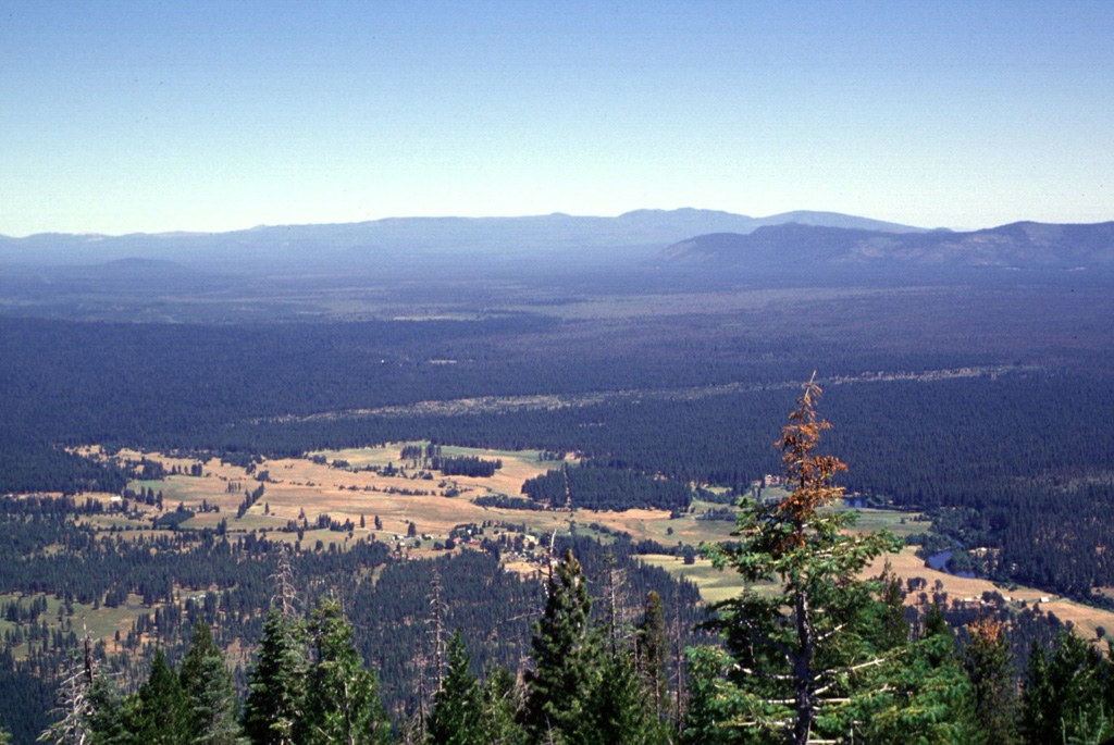 The broad Medicine Lake shield volcano, seen here on the horizon from Soldier Mountain to its south, is truncated by a 7 x 11 km caldera.  Medicine Lake volcano has erupted lavas of widely varying composition ranging from basalt to rhyolite.  The largest eruption of Medicine Lake during the past 11,000 years produced a massive basaltic lava flow from Giant Crater about 10,600 years ago.  The flow traveled a distance of 45 km down the broad valley in the center of the photo from its vent on the SSW flank. Photo by Lee Siebert, 1998 (Smithsonian Institution).