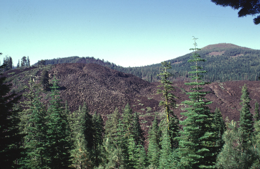 Devils Garden, part of which forms the jumbled blocky lava flows in the foreground, is part of the N-S-trending Tumble Buttes, a young volcanic field located north of Lassen Peak.  The Tumble Buttes field contains some of the youngest volcanic features in this little known area partially within the Thousand Lakes Wilderness Area west of the Hat Creek Valley.  The andesitic lava cone at the upper right is Logan Mountain, of Pleistocene age. Photo by Lee Siebert, 1998 (Smithsonian Institution).