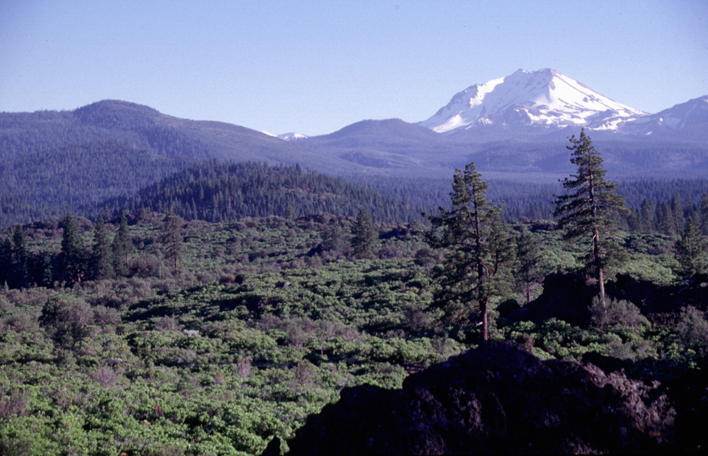 Potato Butte, the forested cinder cone at the left-center, is seen here from the rim of the Hat Creek vent with snow-covered Lassen Peak in the background.  The Potato Butte cinder cones and lava flows were erupted around 65,000-75,000 years ago.  The prominent 30,000-year-old Hat Creek lava flow traveled nearly 30 km from a fissure vent near the town of Old Station.  An undated, but younger-looking flow originated from a cinder cone near West Prospect Peak, west of Potato Butte. Photo by Lee Siebert, 1998 (Smithsonian Institution).