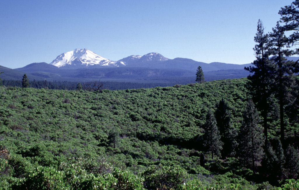 The green Manzanita-covered slope in the foreground is part of the circular rim of South Potato Butte, one of two cinder cones forming Potato Butte.  The two cinder cones fed youthful-looking lava flows down the Hat Creek graben.  Snow-covered Lassen Peak rises in the distance, with the Chaos Crags lava dome complex to its right. Photo by Lee Siebert, 1998 (Smithsonian Institution).