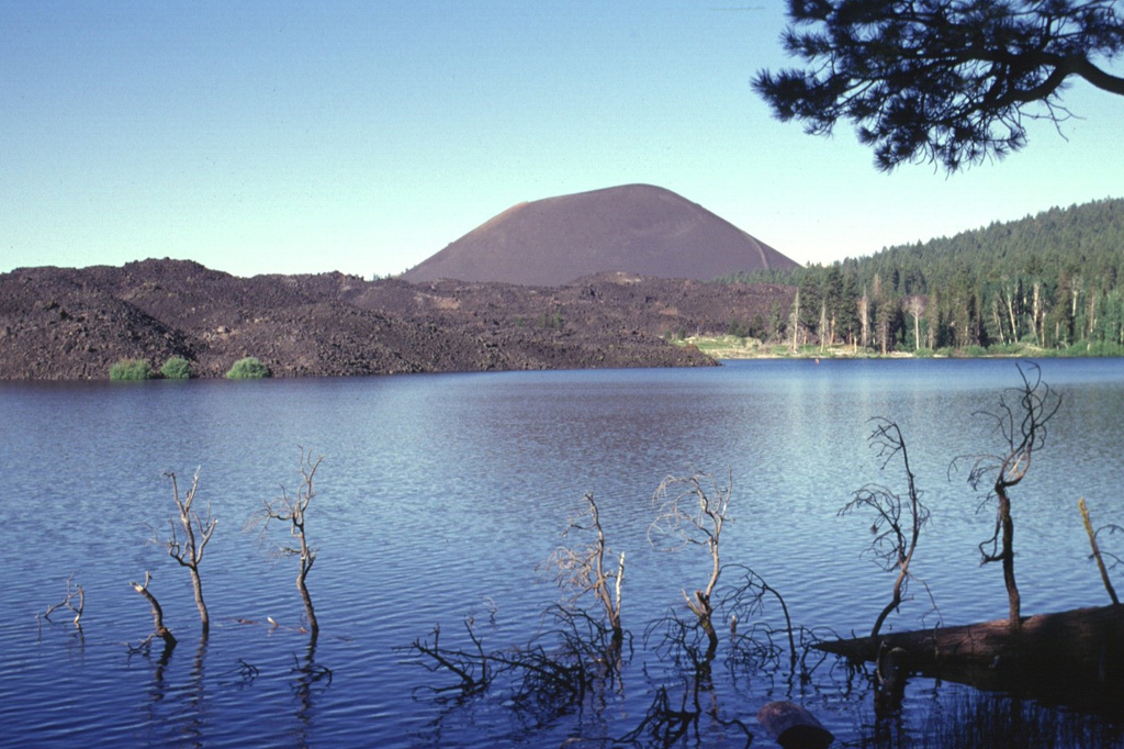 The aptly named Cinder Cone, a symmetrical pyroclastic cone at the NE end of the Lassen volcanic center, is seen here from the NE across Butte Lake.  The unvegetated lava flow at the left originated from the cone.  Although there is a report of an eruption from Cinder Cone in 1850 CE, recent work suggests that the cone and associated lava flows all formed during a brief eruptive interval lasting at most a few decades about 230-425 radiocarbon years ago.  Lava flows traveled to the NE and SE, forming Snag Lake and Butte Lake.   Photo by Lee Siebert, 1998 (Smithsonian Institution).
