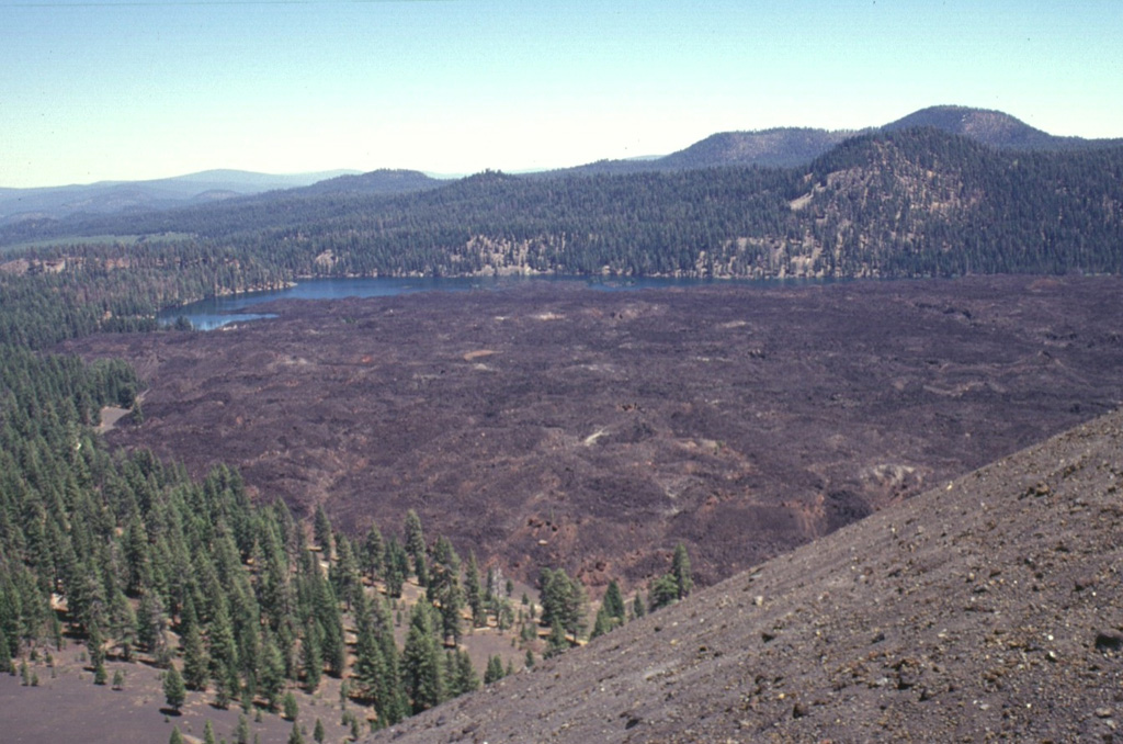 Lava flows traveled about 3.5 km to the north and south from Cinder Cone, blocking drainages and forming two lakes.  The northern lake, Butte Lake, is seen here from the summit of Cinder Cone.  The quartz-bearing basaltic lava flows originated from vents at the SE flank of the pyroclastic cone.  The old Emigrant Trail connecting Nevada with the Sacremento Valley winds through the trees at the left base of the cone. Photo by Lee Siebert, 1998 (Smithsonian Institution).