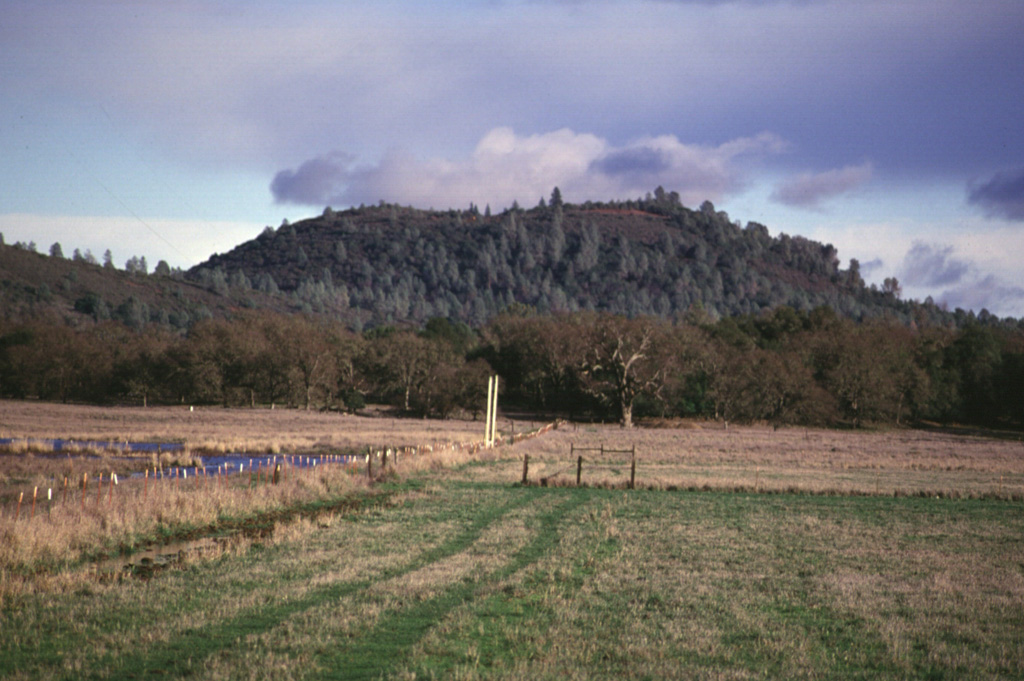 Round Mountain, seen here from the west, rises above the floor of High Valley.  Round Mountain is the northernmost of a N-S-trending chain of basaltic-andesite cinder cones at the eastern end of the Clear Lake volcanic field.  A lava flow from Round Mountain underlies part of the High Valley.  Many of the basaltic-andesite and andesitic lava flows of the Clear Lake field are contaminated with crustal materials.  They often contain xenocrysts of quartz up to several cm in size that are known locally as "Lake County Diamonds." Photo by Paul Kimberly, 1997 (Smithsonian Institution).