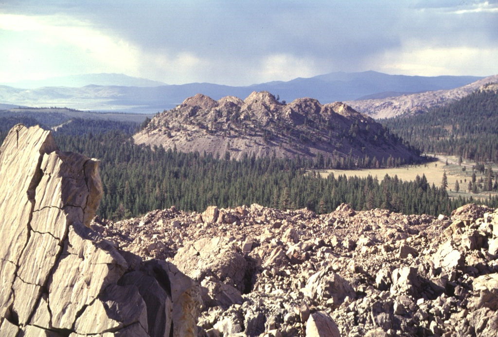 Wilson Butte, the northermost lava dome of the Inyo Craters, is seen from the Obsidian Flow lava dome to the south.  The Inyo Craters are a 12-km-long chain of silicic lava domes, lava flows, and explosion craters along the eastern margin of Sierra Nevada south of Mono Craters near the town of Mammoth.  Inyo Craters overtop the NW rim of the Pleistocene Long Valley caldera and extend onto the caldera floor, but are chemically and magmatically part of a different volcanic system.    The latest eruptions at Inyo Craters took place about 600 years ago. Photo by Lee Siebert, 1998 (Smithsonian Institution).