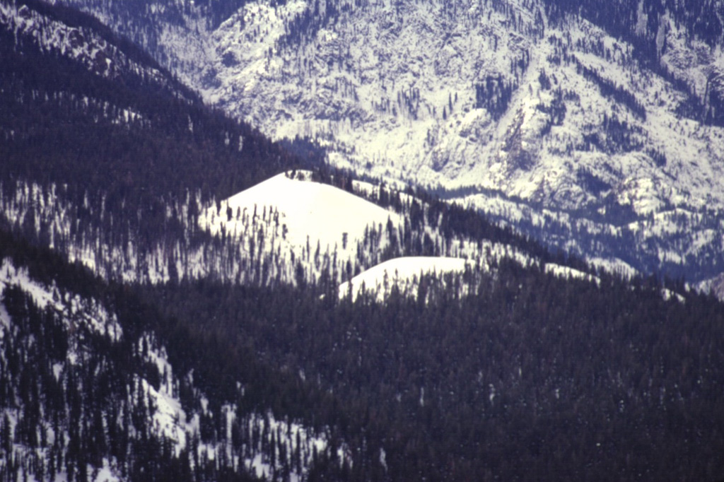 Red Cones, here mantled in winter white in a telephoto view looking SW from Mammoth Mountain, are two young basaltic cinder cones in the eastern Sierra Nevada Mountains near Devils Postpile National Monuement.  The youthful-looking cones are Holocene in age. Photo by Paul Kimberly, 1997 (Smithsonian Institution).