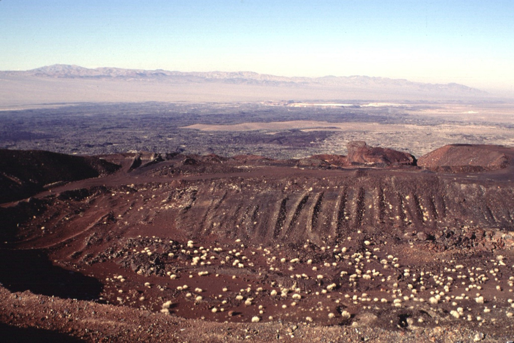 The cone of Pisgah Crater has been modified by mining operations that provide a source of road aggregate.  The cone is the most prominent feature of the Lavic Lake volcanic field in southern California.  A broad lava field erupted from nearby vents surrounds the cone; a narrow lobe that extends up to 18 km to the NW can be seen in this view. Photo by Lee Siebert, 1997 (Smithsonian Institution).