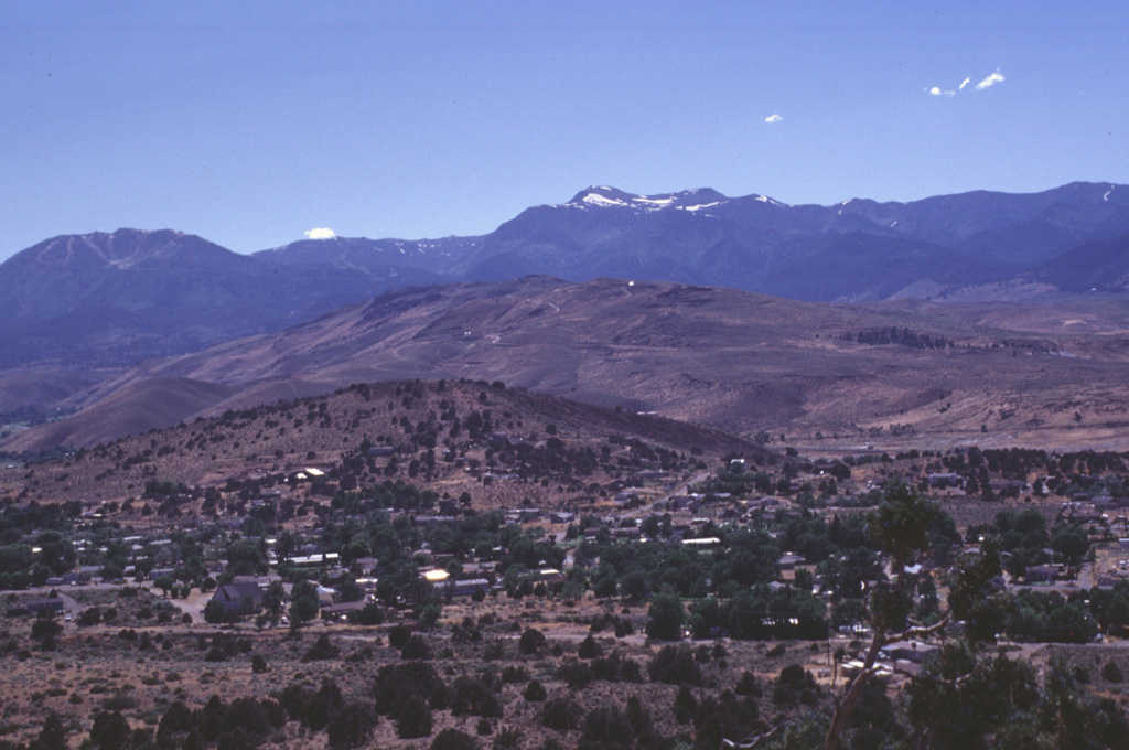 The Steamboat Hills in the center of the photo is an area of geothermal development in the Steamboat Springs volcanic field of western Nevada.  The small light spot just right of the summit of the central hill is a steam plume from a geothermal well.  Steamboat Springs lies in a structural trough in the eastern Sierra Nevada between the Virginia Range on the east and the western Carson Range in the background of the photo. Photo by Lee Siebert, 1998 (Smithsonian Institution)