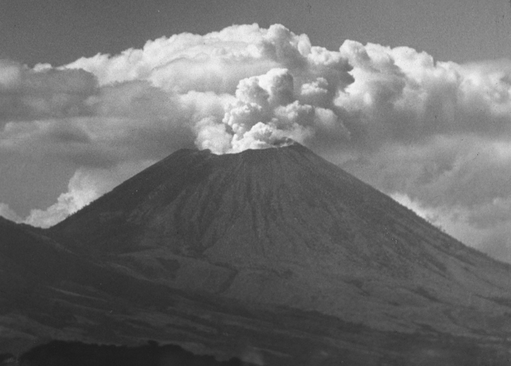 A vigorous steam plume pours from the summit crater of San Cristóbal volcano in December 1971, following an eruption that began on May 3.  This mild explosive eruption lasted until early July.  The 1971 activity marked the first documented eruptive activity at San Cristóbal since the 17th century.  The volcano is seen here from the El Limón gold mine east of the volcano. Photo by Dick Stoiber, 1971 (Dartmouth College).