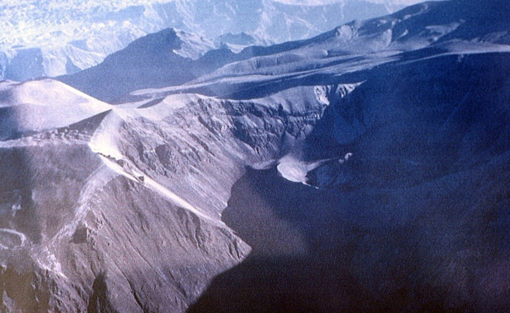 Huaynaputina is a relatively inconspicuous volcano that was the source of one of the largest historical eruptions of the central Andes in 1600 CE.  The volcano has no prominent topographic expression.  This view is from the east into a 2.5-km-wide complex caldera that is breached widely to the east.  Three ash cones, one of which can be seen in the shadow at the right-center, are located on the floor of the caldera.  Light-colored ash deposits from the 1600 eruption can be seen mantling the caldera rim.   Photo by Oscar González-Ferrán (University of Chile).