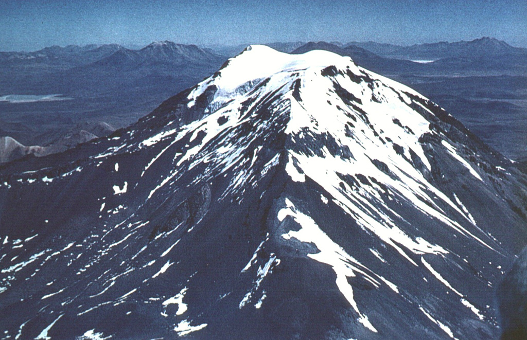 Glacier-capped Cerro Capurata lies at the southern end of the Nevados de Quimsachata volcano group.  Quimsachata means "three" in the Andean Aymará language, and Capurata, along with 5730-m-high Humarata at the northern end of the chain and 6052-m-high Acotango in the center, straddles the Chile-Bolivia boundary along a roughly N-S line.  The 6052-m-high Acotango stratovolcano is the central and highest of the three stratovolcanoes, each of which may have been active during the Holocene. Photo by Sergio Kunstmann-Z (courtesy of Oscar González-Ferrán, University of Chile).