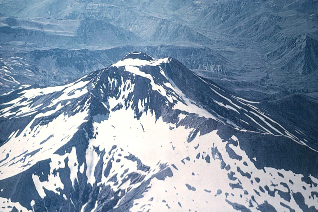 A young scoria cone rises above the glacier-filled summit crater of 3621-m-high San Pedro stratovolcano, viewed here from the NW.  The San Pedro-Pellado complex was constructed within the 6 x 12 km Río Colorado caldera, which formed during an eruption about 0.5 million years ago.  San Pedro volcano itself is of Holocene age.  No historical eruptions have been recorded from San Pedro-Pellado, but fumaroles are found SE of Pellado.      Photo by Oscar González-Ferrán (University of Chile).